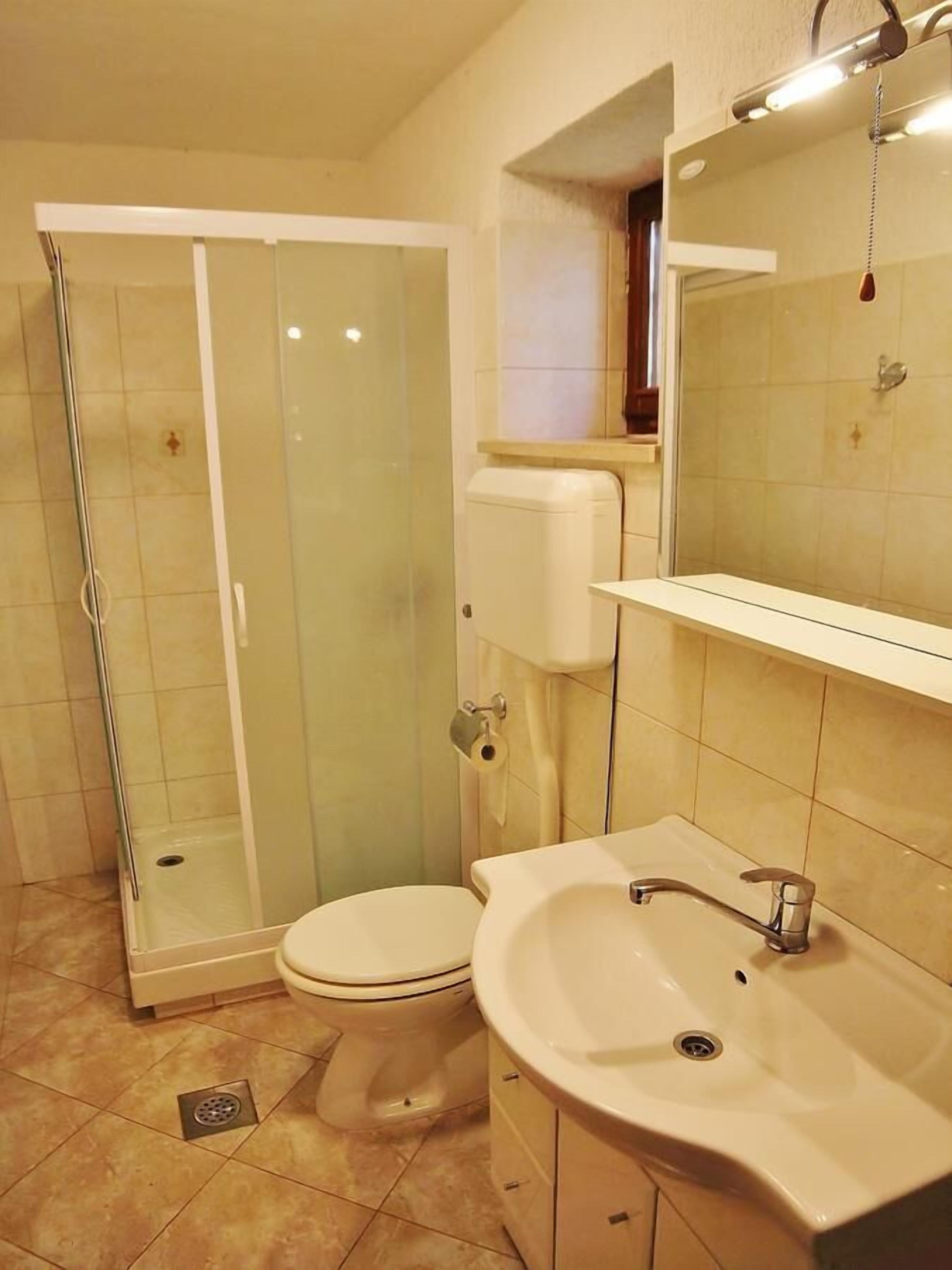 A bathroom with a glass-enclosed shower, a toilet, a sink, and a mirror.