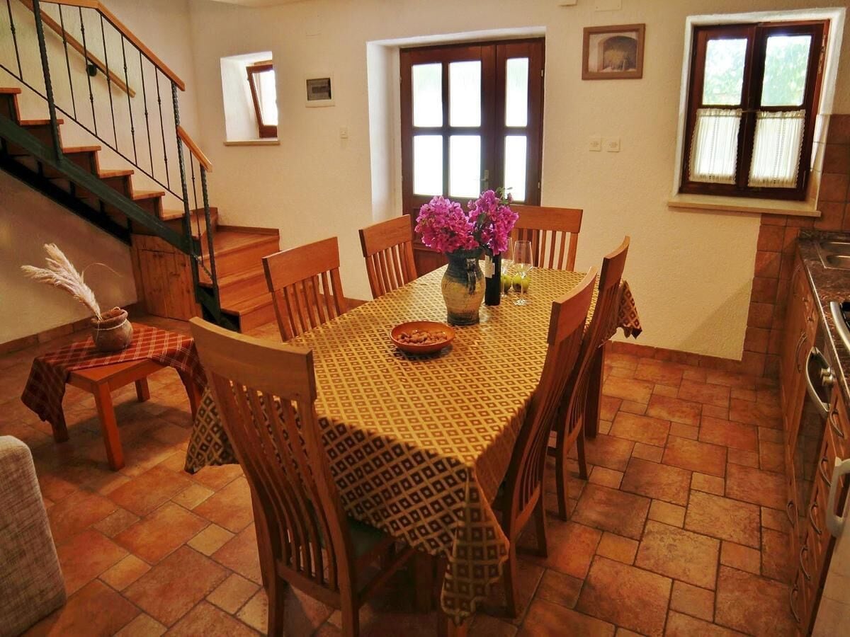 A dining area with a wooden table, chairs, and a vase of flowers.