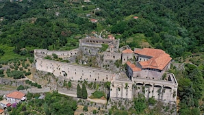 Vista aérea de un complejo de castillos históricos con murallas fortificadas, varios edificios y abundante vegetación circundante.