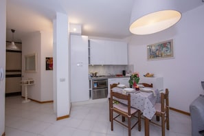 Modern kitchen and dining area with a stainless steel oven, microwave, and dining table for four.