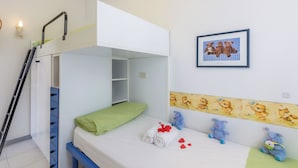 Une chambre avec un lit superposé, une échelle, un oreiller vert et un mur décoré de motifs représentant des ours en peluche.
