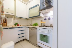 A compact kitchen with white cabinets, a dishwasher, an oven, and a gas stove.