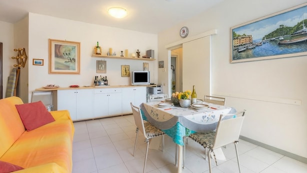 Un coin repas avec une table dressée pour deux personnes, un canapé et une cuisine en arrière-plan.