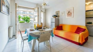 Un coin repas avec une table dressée pour deux personnes, un canapé et un ventilateur de plafond.