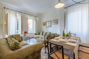 Een goed verlichte woonkamer met een bank, een eettafel voor vier personen en een salontafel.