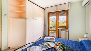 Un dormitorio con cama, ventana con vistas, radiador y armario.