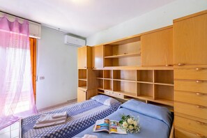 Ein Schlafzimmer mit zwei Betten, einem Holzschrank und einem Fenster mit Vorhängen.