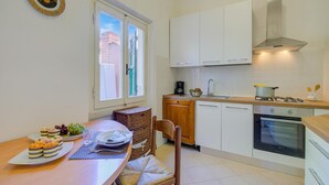 A kitchen with white cabinets, a stove, and a window with a view of buildings. - La Fresia - Focette 100mt From Sea (Pietrasanta)