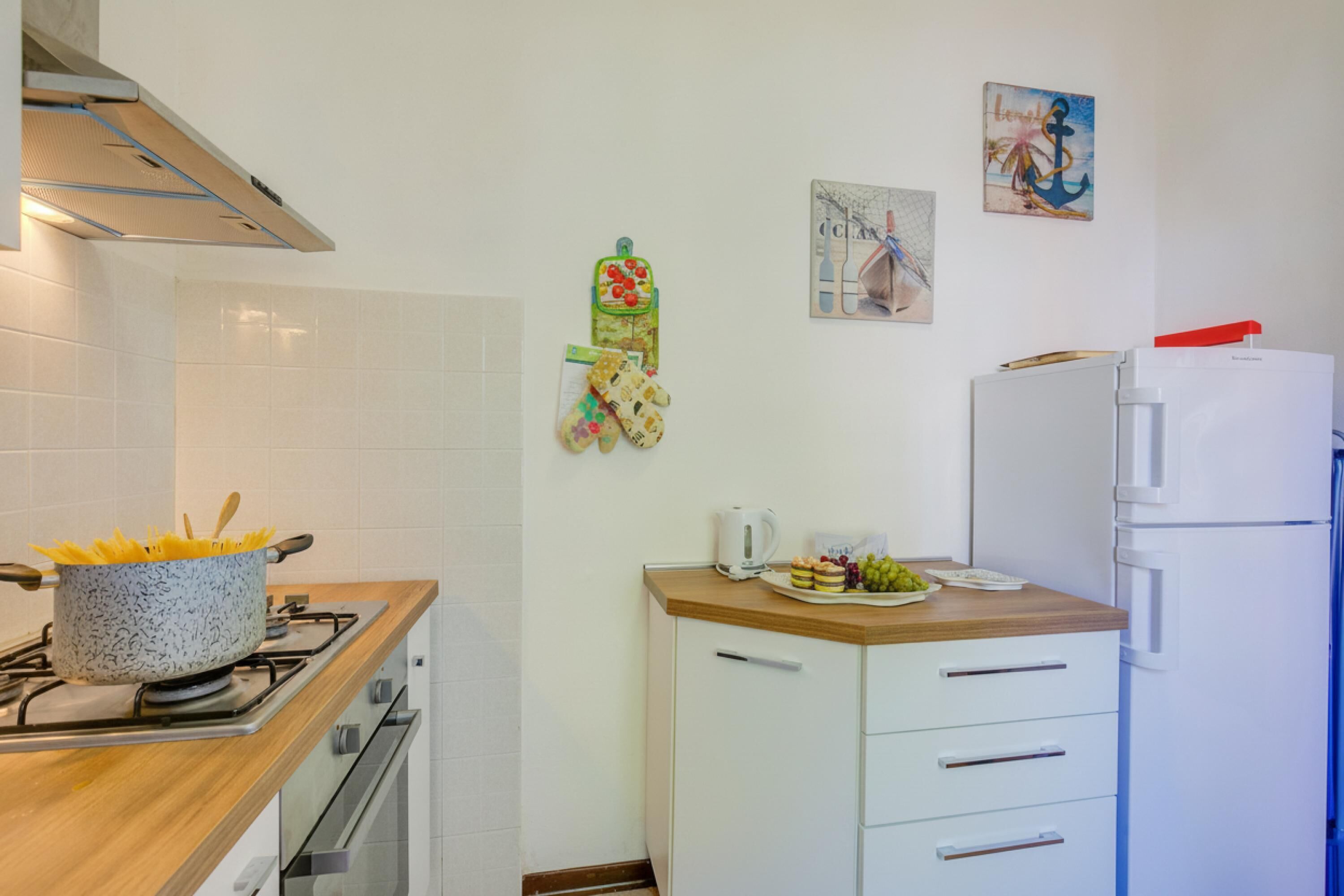 Eine Küche mit Herd, Kühlschrank und einer Arbeitsplatte mit Wasserkocher und einem Teller Essen.