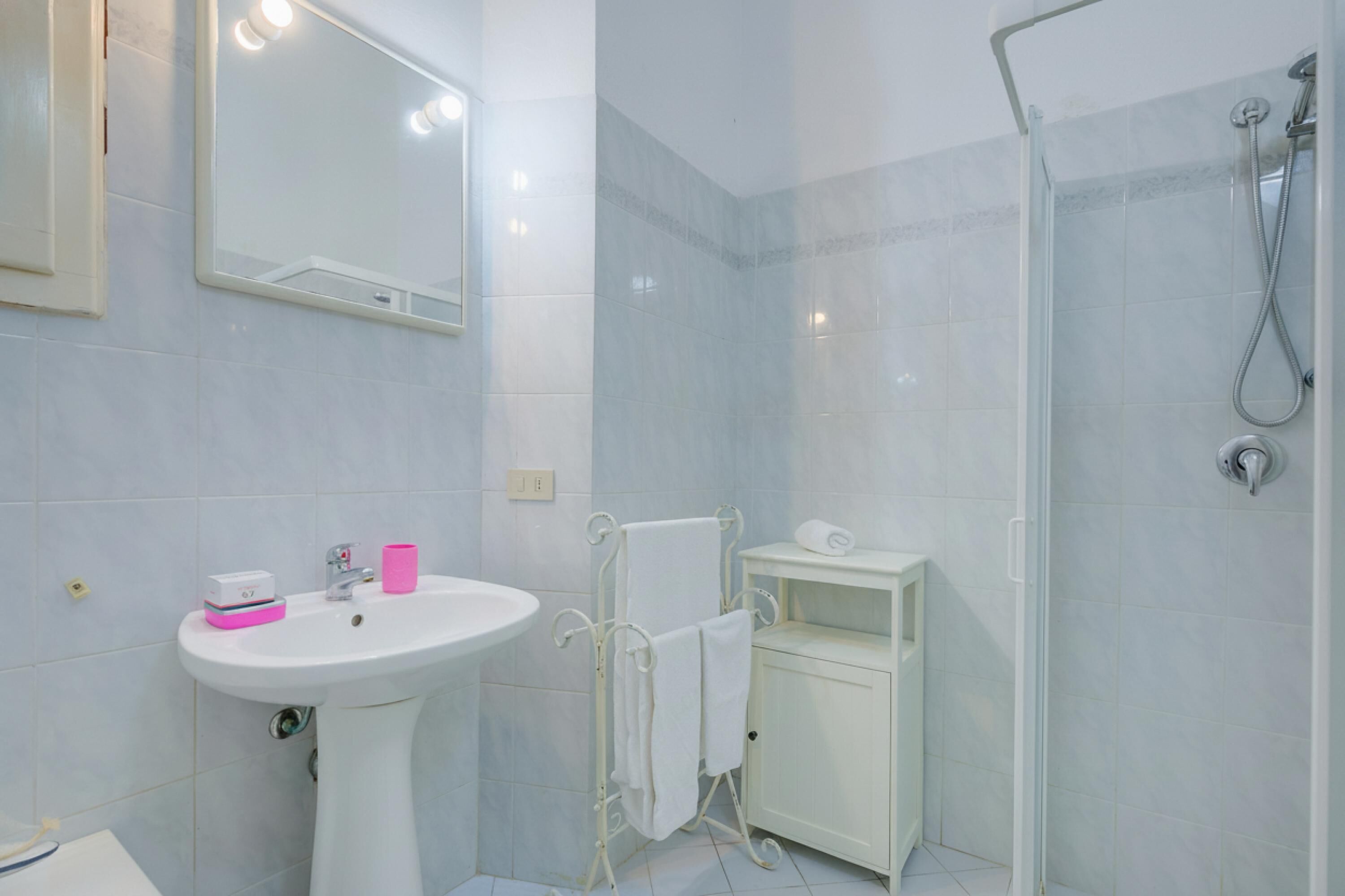 A bathroom with a sink, mirror, shower, and a cabinet.