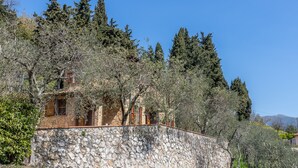 A stone-walled building with wooden windows, surrounded by trees and a clear blue sky. - La Maggioletta (Massarosa)