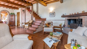 A cozy living room with a fireplace, comfortable seating, and a staircase leading to another level. - La Maggioletta (Massarosa)