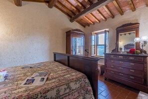 A bedroom with a bed, a dresser, a mirror, and a window.