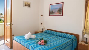Habitación de hotel con cama, mesita de noche, lámpara y un cuadro en la pared.