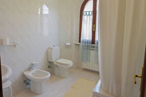 A bathroom with a bidet, toilet, and sink.