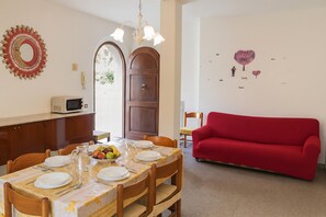 A dining area with a table set for four, a red sofa, and a wall with decorative elements.