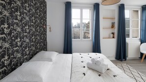 Une chambre d’hôtel moderne avec un grand lit, une vue sur la ville et une bibliothèque.