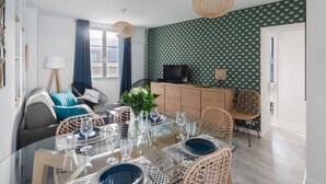 Un coin repas avec une table en verre dressée pour six personnes, entourée de chaises en osier.