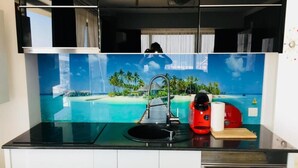 Eine Küche mit schwarzer Arbeitsplatte, einem Spülbecken und einer roten Kaffeemaschine.