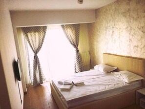 A hotel room with a bed, a nightstand, and a window with curtains. - Mamaia Rent Apartments (Constanta)
