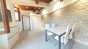 Cocina moderna con armarios blancos, una pared de acento de piedra y un comedor con mesa y sillas.