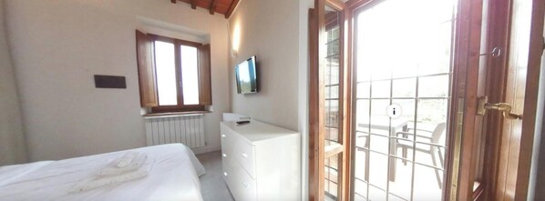 A bedroom with a bed, a dresser, a television, and a window.