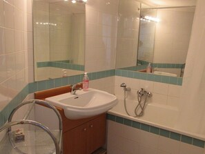 A bathroom with a white sink, a mirror, and a shower.
