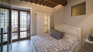 Ein Schlafzimmer mit einem großen Bett, einer Holzbalkendecke und Blick durch eine Glastür.