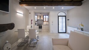 Ein modernes Wohnzimmer mit einer Couch, einem Esstisch mit Stühlen und einer Küche im Hintergrund.
