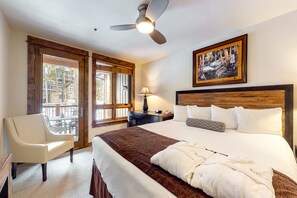 Relax in a spacious room with a large bed, ceiling fan, and a seating area with a comfortable armchair.