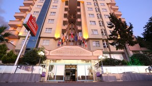 A multi-story hotel with a central entrance, balconies, and flags.