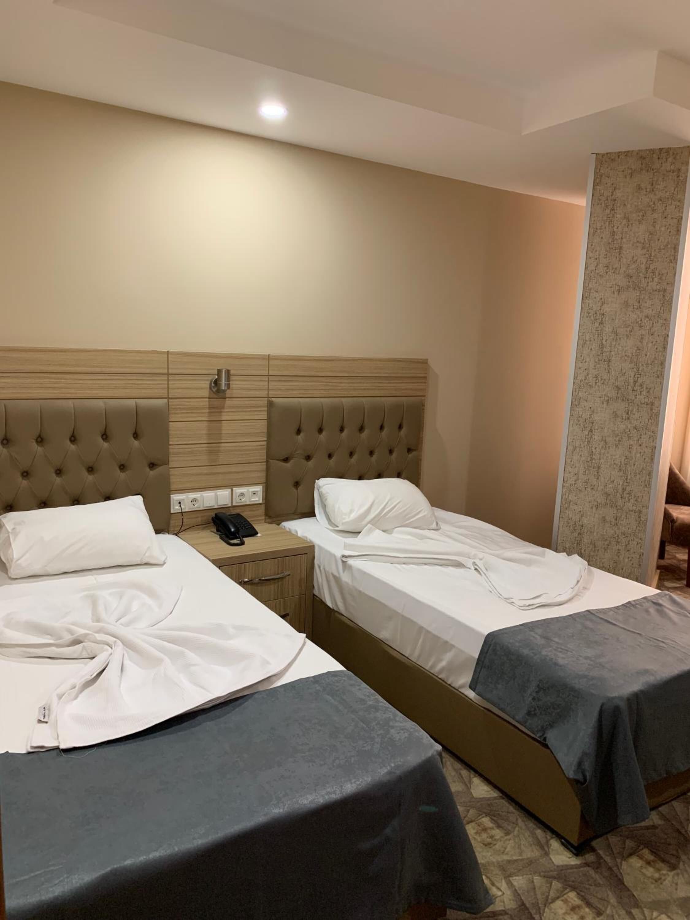 Una habitación de hotel con dos camas, cada una con cabecera y mesita de noche.