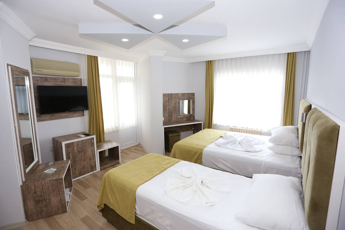 A hotel room with two beds, a TV, a desk, and a mirror.