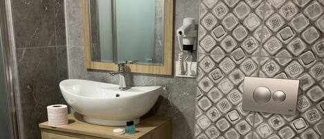 A modern bathroom with a marble sink, a mirror, a toilet, and patterned tiles.