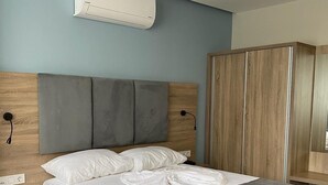 A bedroom with a bed, bedside tables, a wardrobe, and an air conditioning unit.
