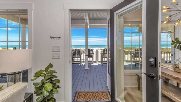 A modern interior with a view of the beach through an open door.