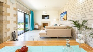 A modern living room with a sofa, a dining table with a glass top, and a fireplace.
