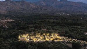 A hotel with multiple buildings surrounded by dense vegetation and mountains in the background.