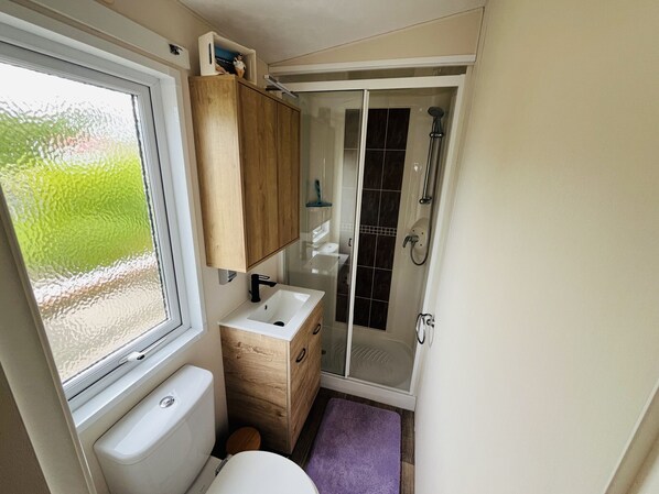 A compact bathroom with a toilet, sink, and shower.