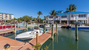 A marina with boats docked, a wooden dock, and a building with a blue roof. - Dbl Master |Oceanview |Jacuzzi |Beach |Marina |BBQ (Tavernier)