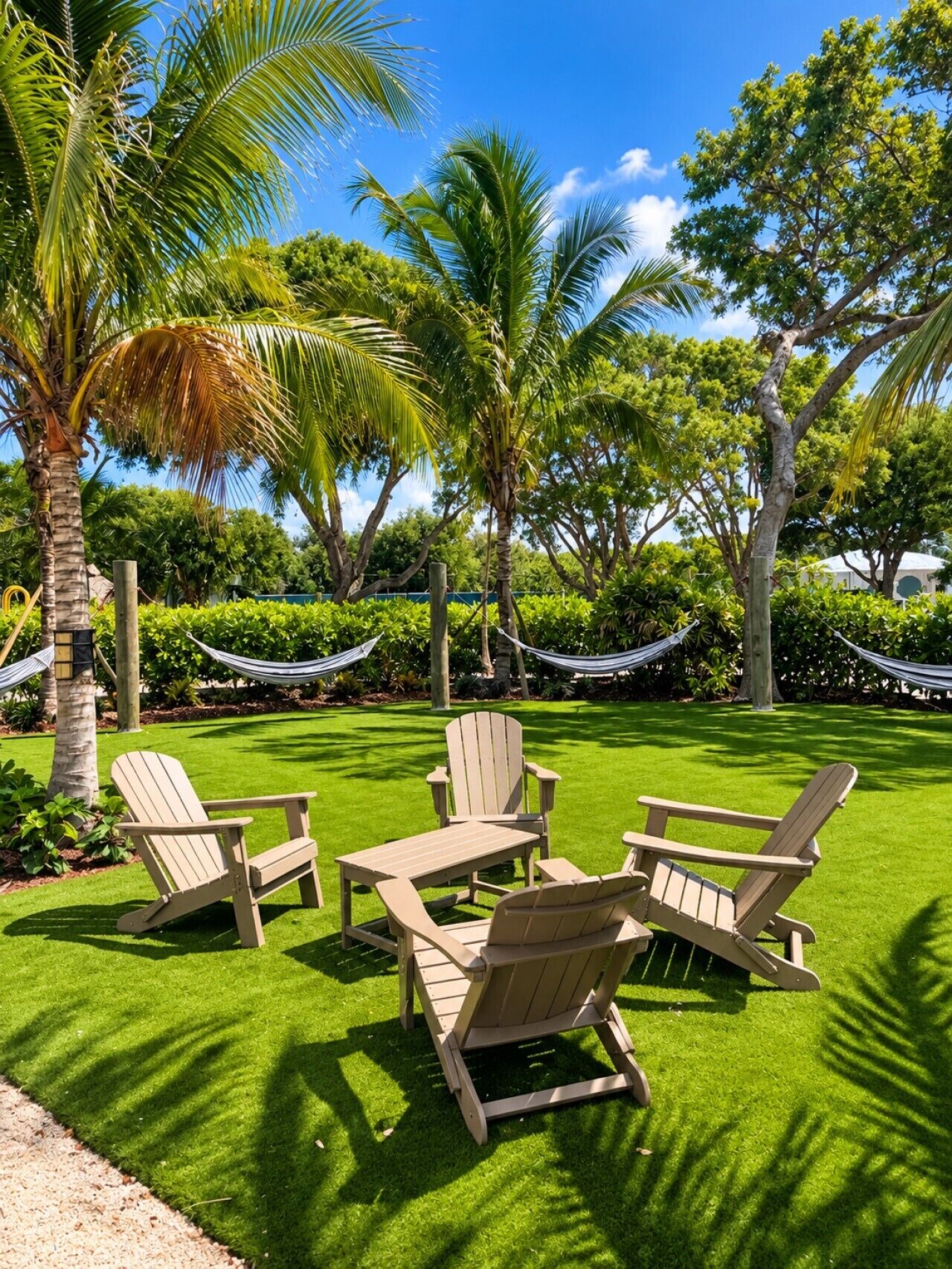 A well-maintained lawn with four Adirondack chairs and a hammock.