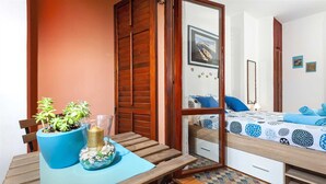 Un dormitorio acogedor con cama, una mesita de noche con planta en maceta y espejo.