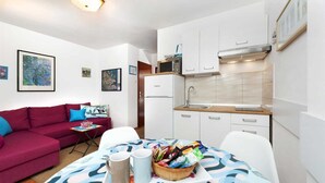 Un espacio habitable compacto con kitchenette, un sofá rojo y una zona de comedor con una bandeja de aperitivos.