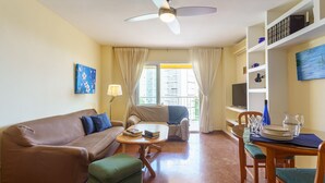 A living room with a sofa, ottoman, coffee table, and a dining area with a table and chairs. - MalagaSuite Beautiful Coast (Torremolinos)