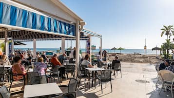Ein Straßencafé mit Tischen und Stühlen mit Blick auf den Strand.