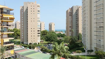 Ein Hochhaus mit mehreren Balkonen, einem Grünflächen-Sportplatz und einer Palme im Vordergrund.