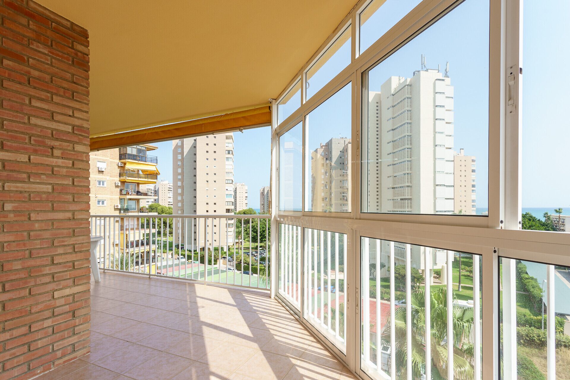 Een balkon met uitzicht op hoge gebouwen en een heldere lucht.