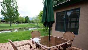 A wooden deck with wicker furniture and a glass table, overlooking a pond and a golf course. - Dalton Ranch Townhome on 11th Fairway & Waterway - A/C - Unbeatable Views (Durango)