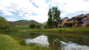 A serene lakeside view with a modern building featuring large windows and a flat roof. - Dalton Ranch Townhome on 11th Fairway & Waterway - A/C - Unbeatable Views (Durango)
