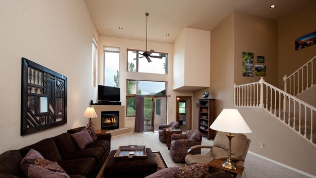 A spacious living room with a fireplace, a television, and a staircase leading to an upper level. - Dalton Ranch Townhome on 11th Fairway & Waterway - A/C - Unbeatable Views (Durango)